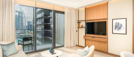 A modern living room with a large TV, comfortable seating, a small coffee table, and a view of a cityscape through large windows.
