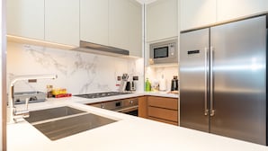 A modern kitchen with a stainless steel refrigerator, a microwave, and a stove. - Luxury StayCation - Modern Comfort: 3-BR at The Address Opera (Dubai)