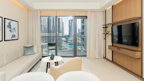 A modern living room with a large window, a sofa, a coffee table, and a flat-screen TV. - Luxury StayCation - Modern Comfort: 3-BR at The Address Opera (Dubai)