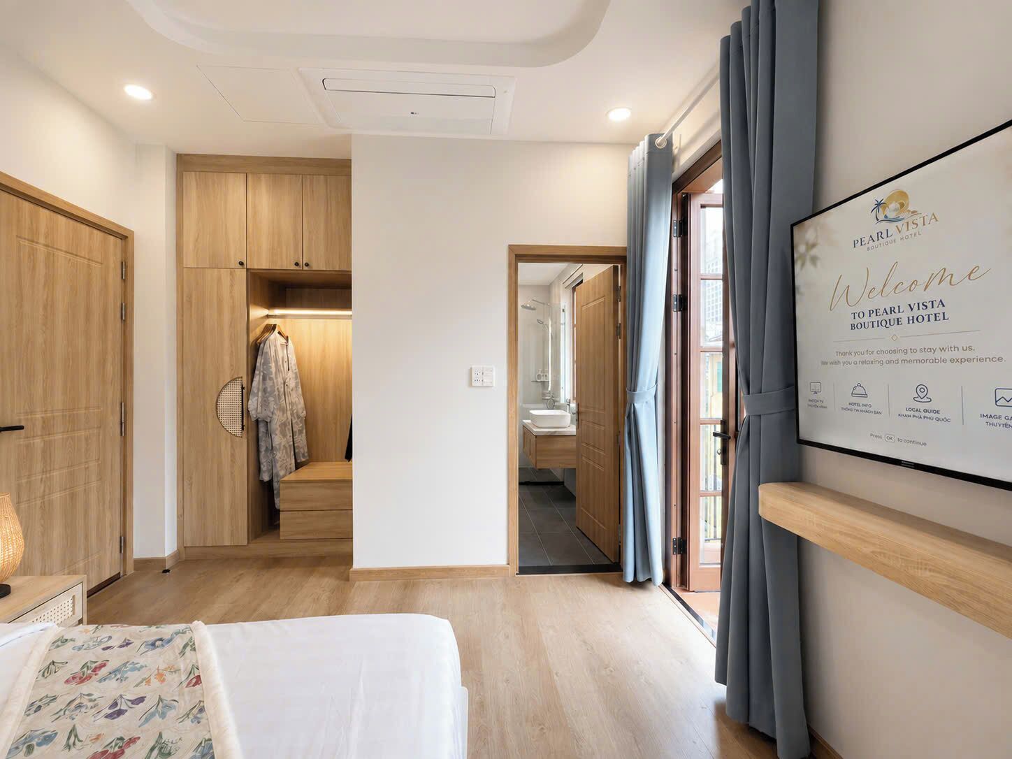 Hotelkamer met een bed, een kledingkast, een spiegel en een wandgemonteerde tv met een welkomstbericht van het hotel.