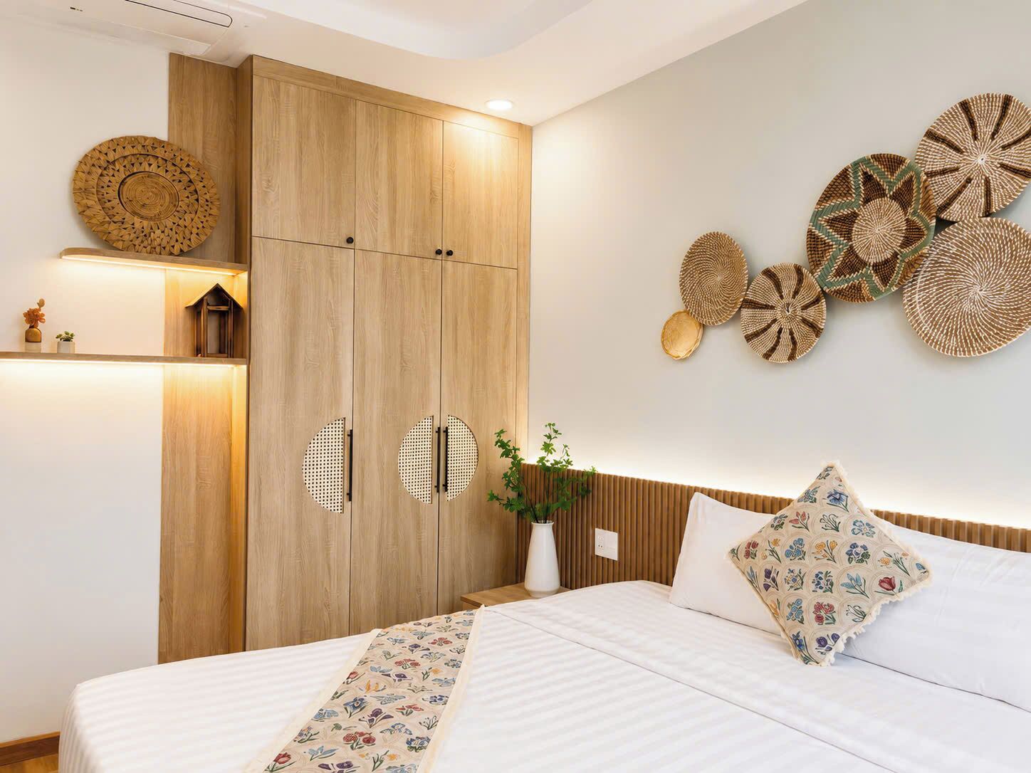A bedroom with a bed, a wooden wardrobe, and decorative wall art.