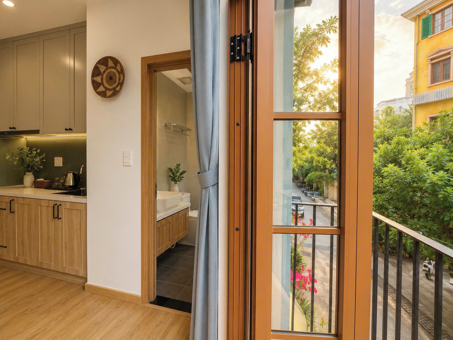 A modern kitchen with wooden cabinets, a sink, and a window overlooking a street with greenery.
