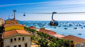 A cable car system over a coastal town with buildings and boats in the water.
