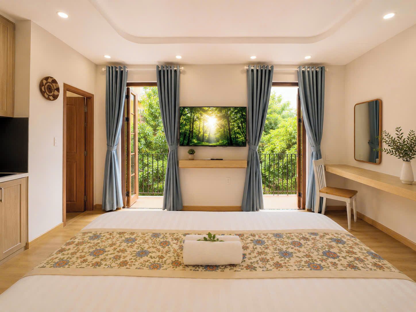 A bedroom with a bed, a TV, a desk, and a balcony with curtains.