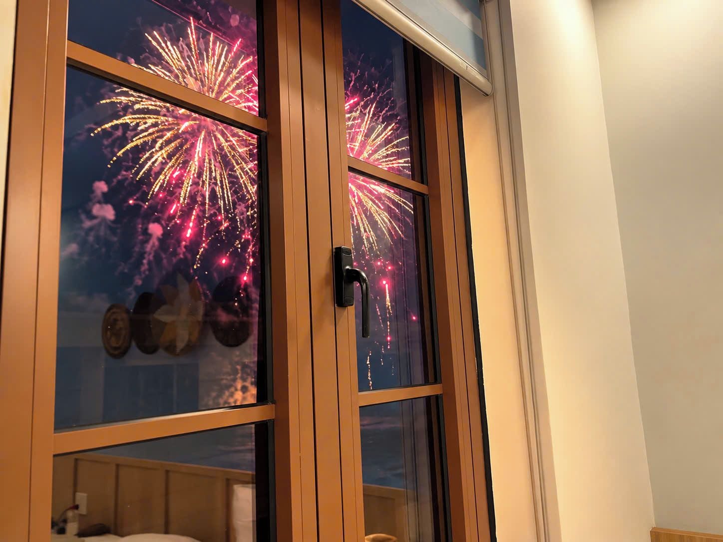 Una habitación con un ventanal que muestra fuegos artificiales.