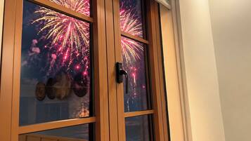 Una habitación con un ventanal que muestra fuegos artificiales.