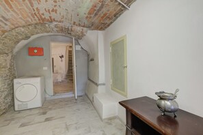 Cozy apartment with a laundry machine, small table, and stone archway.