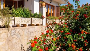A white building with a stone wall and a decorative railing.