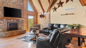 A cozy living room with a stone fireplace, leather furniture, and wooden beams. - Pet + Family Friendly, 4 mins to Golf, on the Bourbon Trail, & close to the Ark! (Owenton)