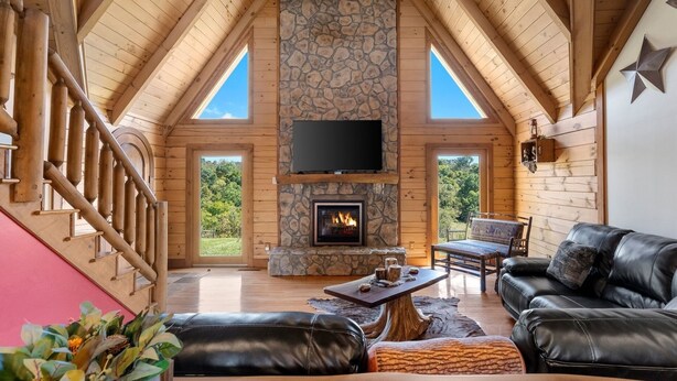 A spacious living room with a stone fireplace, leather furniture, and a TV mounted above it. - Pet + Family Friendly, 4 mins to Golf, on the Bourbon Trail, & close to the Ark! (Owenton)