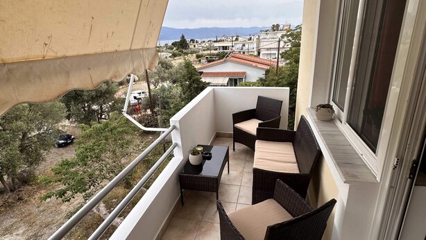 Uma varanda com mobiliário de vime, uma pequena mesa e vista para os arredores.