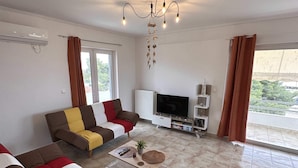Uma sala de estar com sofá, mesa de centro, televisão e radiador.