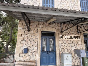 A building with a stone facade, a blue door, and a sign with Greek text. - VerGian Brand New Apt at Agioi Theodoroi (Loutraki-Agioi Theodoroi)