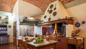 Een keuken met een bakstenen plafond, een grote kookplaat en diverse keukengerei.