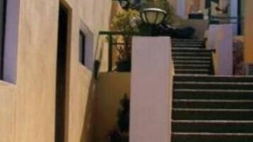 A hotel entrance with a staircase leading to the main building, surrounded by a garden with flowers.