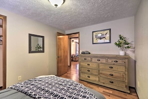 Quarto com uma cama, penteadeira, espelho e um quadro na parede.