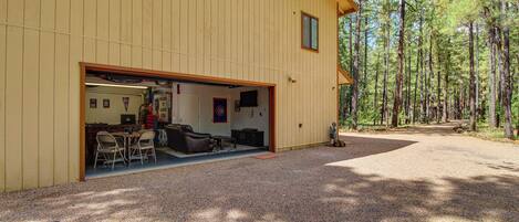A wooden building with an open garage and a covered outdoor seating area.