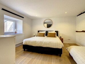 A bedroom with a large bed, a smaller bed, a window, a mirror, and a radiator. - L'Héritage de Durbuy, Luxurious Villa perfect for families or groups of friends (Durbuy)