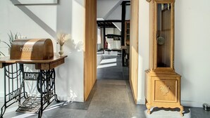 Un couloir orné d’une horloge en bois d’époque, d’un barbecue de la marque Necci et d’une machine à coudre.