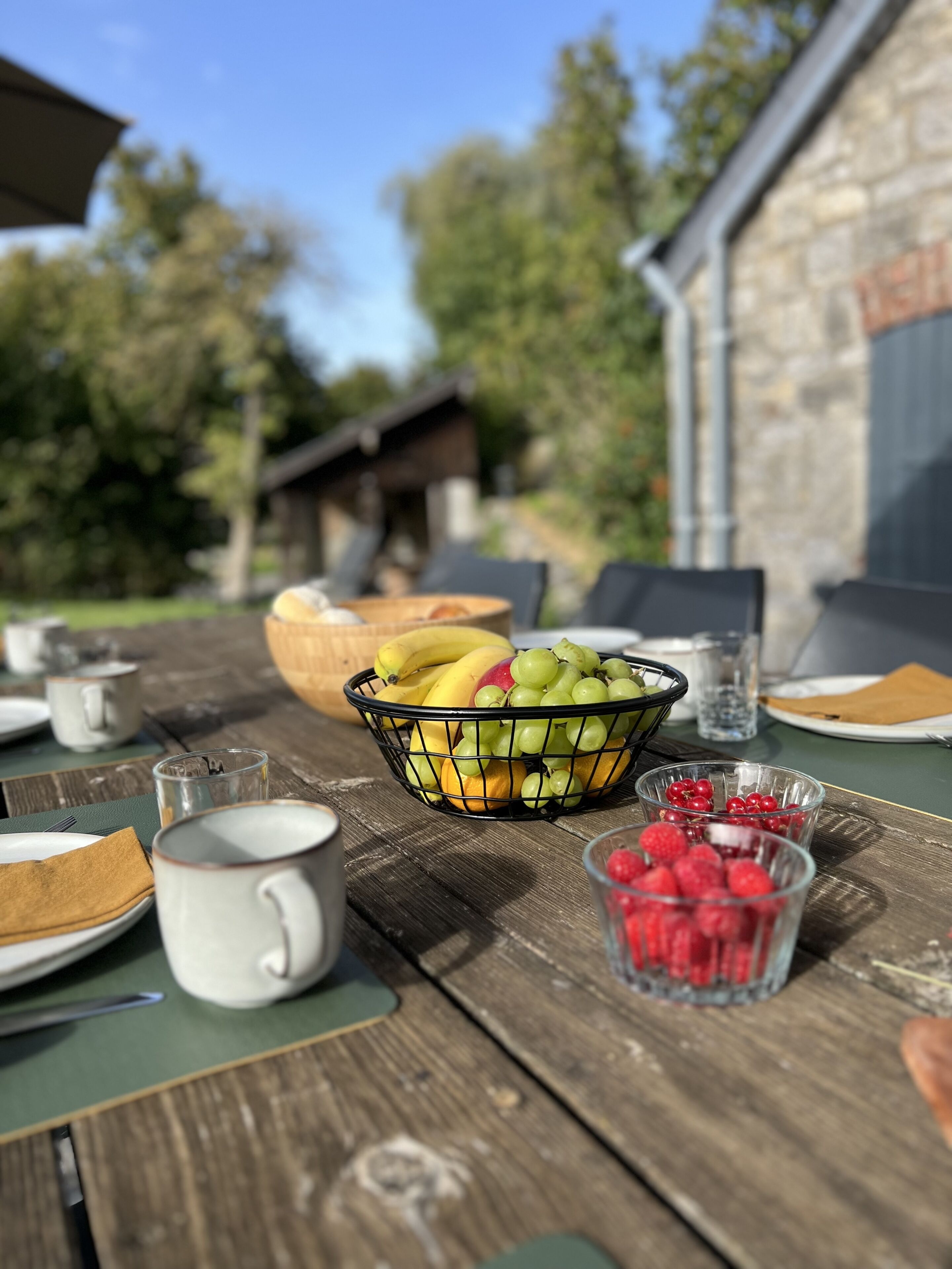 Een houten tafel met een fruitmand, een glas water en een mok.