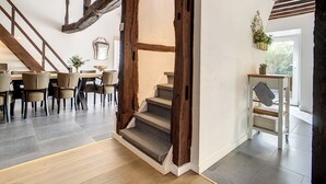 Un intérieur moderne avec un escalier, un coin repas et une petite table agrémentée d’une plante.