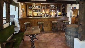 A rustic bar with wooden furniture, a tiled floor, and a variety of bottles on shelves. - The White Horse Inn (Shrewsbury)