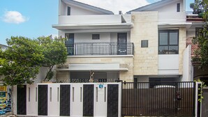 A modern two-story building with a gated entrance, a balcony on the upper floor, and a stone facade. - OYO 93500 Rizki Residence TOS Syariah Near PT Bank KB Bukopin Tbk (Jakarta)
