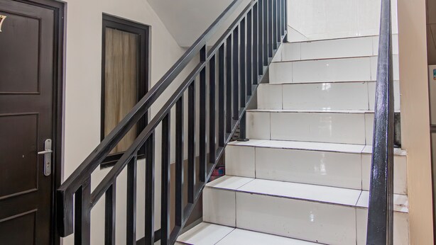 A staircase with white steps and black railings, leading to a landing. - OYO 93500 Rizki Residence TOS Syariah Near PT Bank KB Bukopin Tbk (Jakarta)