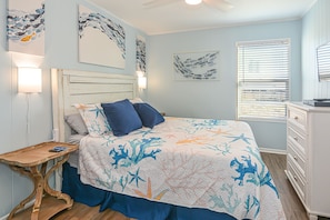 Un dormitorio con cama, mesita de noche, cómoda y decoración en la pared.