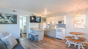 A modern kitchen with a central island, white cabinets, and a dining area with a wooden table and benches.