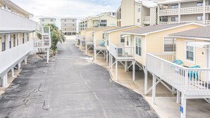 A row of beachfront mobile homes with balconies, a clear sky, and a paved street.
