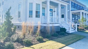 A two-story residential building with a front porch, a covered entryway, and a visible staircase leading to the entrance. - Pebble Beach East Home with Bay Creek Amenities (Cape Charles)