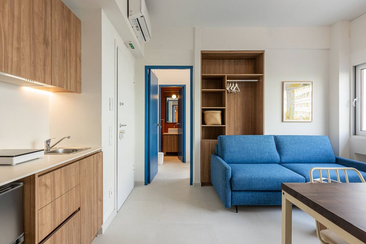 A compact living space with a kitchenette, a blue sofa, and a dining area.