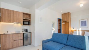 A compact living space with a kitchenette, a sofa, and a wooden bench. - Kallithea Apartments by Olala Homes (Kallithea)