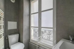 Une salle de bain avec des toilettes, une fenêtre et un lavabo.