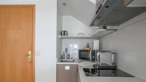 A compact kitchen with a microwave, toaster, and a small refrigerator. - Paris, Opéra 1... Comme Chez soi (Paris)