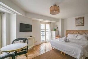 A bedroom with a bed, a TV, a desk, and a chair. - Paris, Opéra 1... Comme Chez soi (Paris)