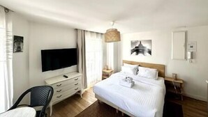 Ein Hotelzimmer mit Bett, Fernseher, Schreibtisch und Stuhl.