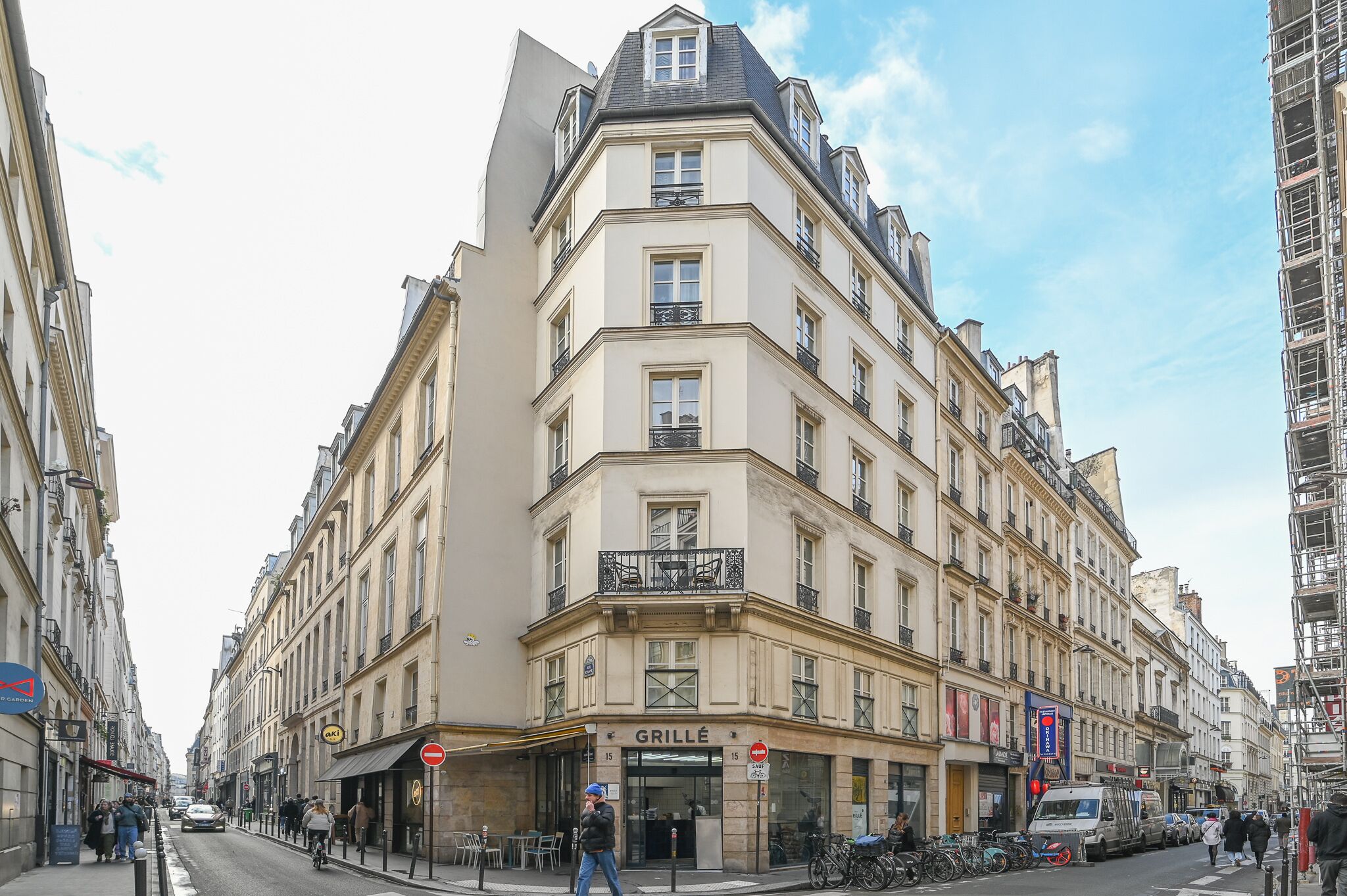 A corner building with a 'GRILLE' sign, multiple balconies, and a parked van.