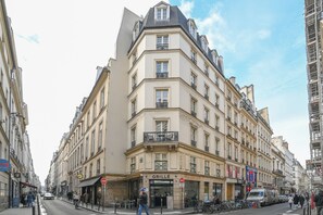 Un edificio en esquina con un letrero que dice 'GRILLE', varios balcones y una furgoneta estacionada.