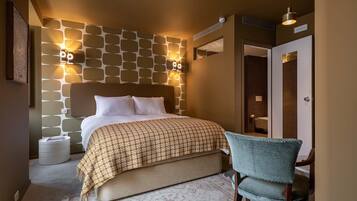 A bedroom with a bed, bedside lamps, a chair, and a patterned rug.