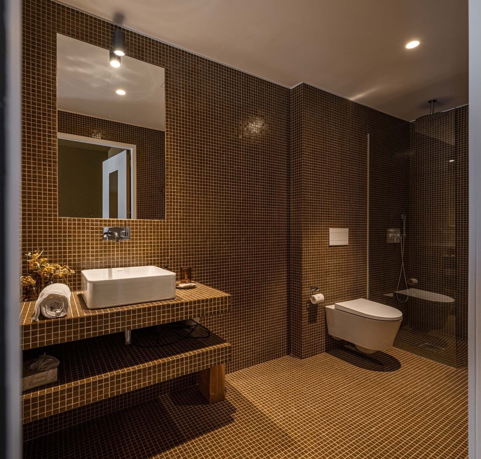 Une salle de bain moderne avec un grand miroir, un lavabo blanc et des toilettes séparées.