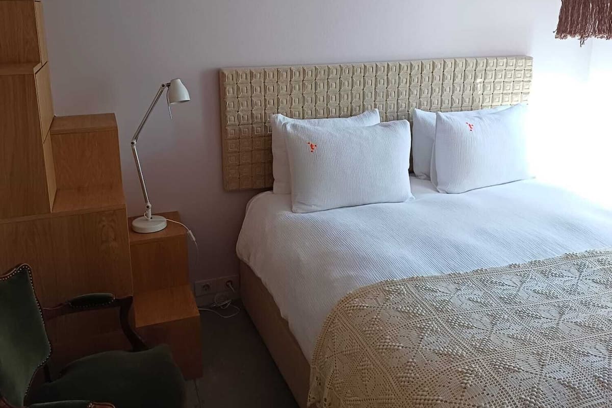 A bedroom with a bed, a desk, a chair, and a lamp.