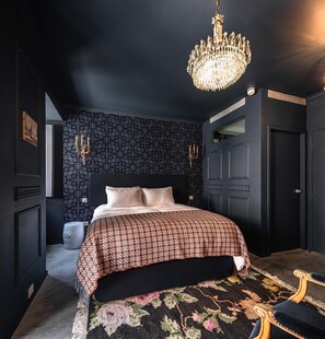 A bedroom with a large bed, a chandelier, a patterned wall, and a door. - toctoctocLisboa (Lisbon)