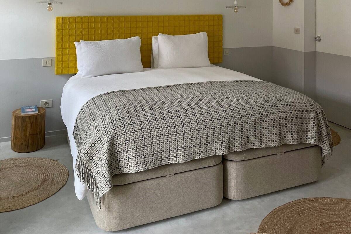 A bedroom with a bed, bedside tables, a hanging light fixture, and a door.