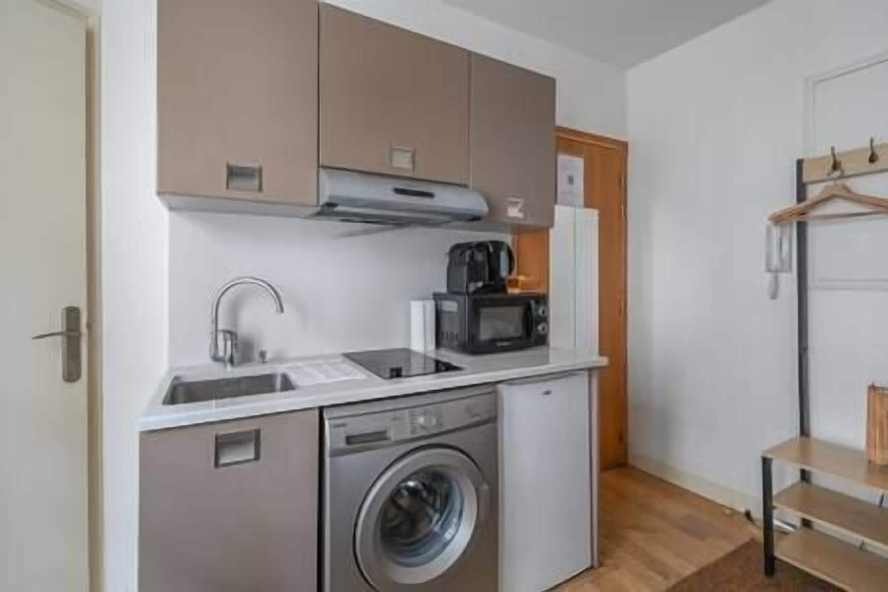 A compact kitchen with a washing machine, a microwave, and a coffee maker.