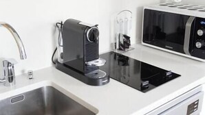 A kitchen with a coffee maker, microwave, and sink.