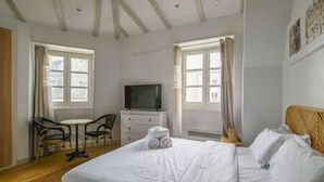 A hotel room with a bed, a TV, a desk, and two chairs.