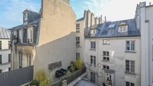 Un immeuble à plusieurs étages, doté d’un toit plat et d’un balcon orné de plantes en pot.
