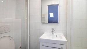 A bathroom with a white sink, a mirror, and a blue door. - Romantic apartment in central Paris (Paris)